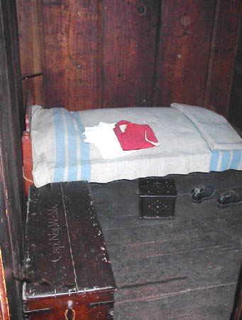 Colonial era bedroom with shoes, chect, bed and charcoal heater